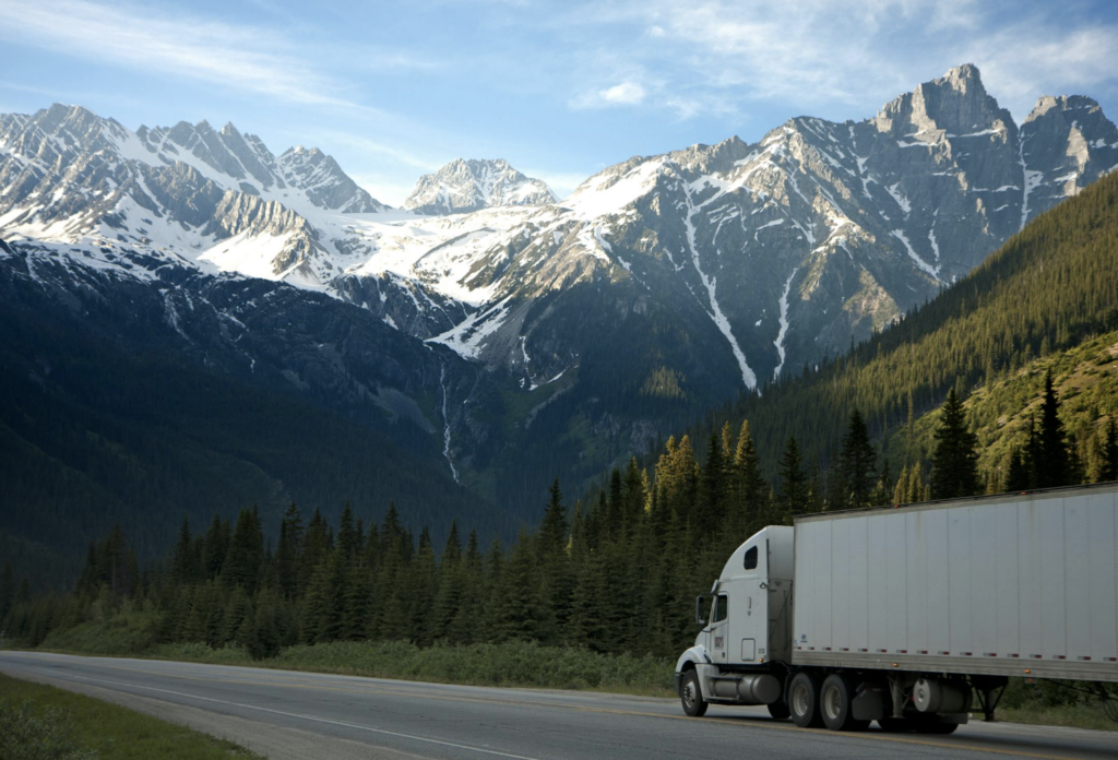 semi truck driving toward a mountain range